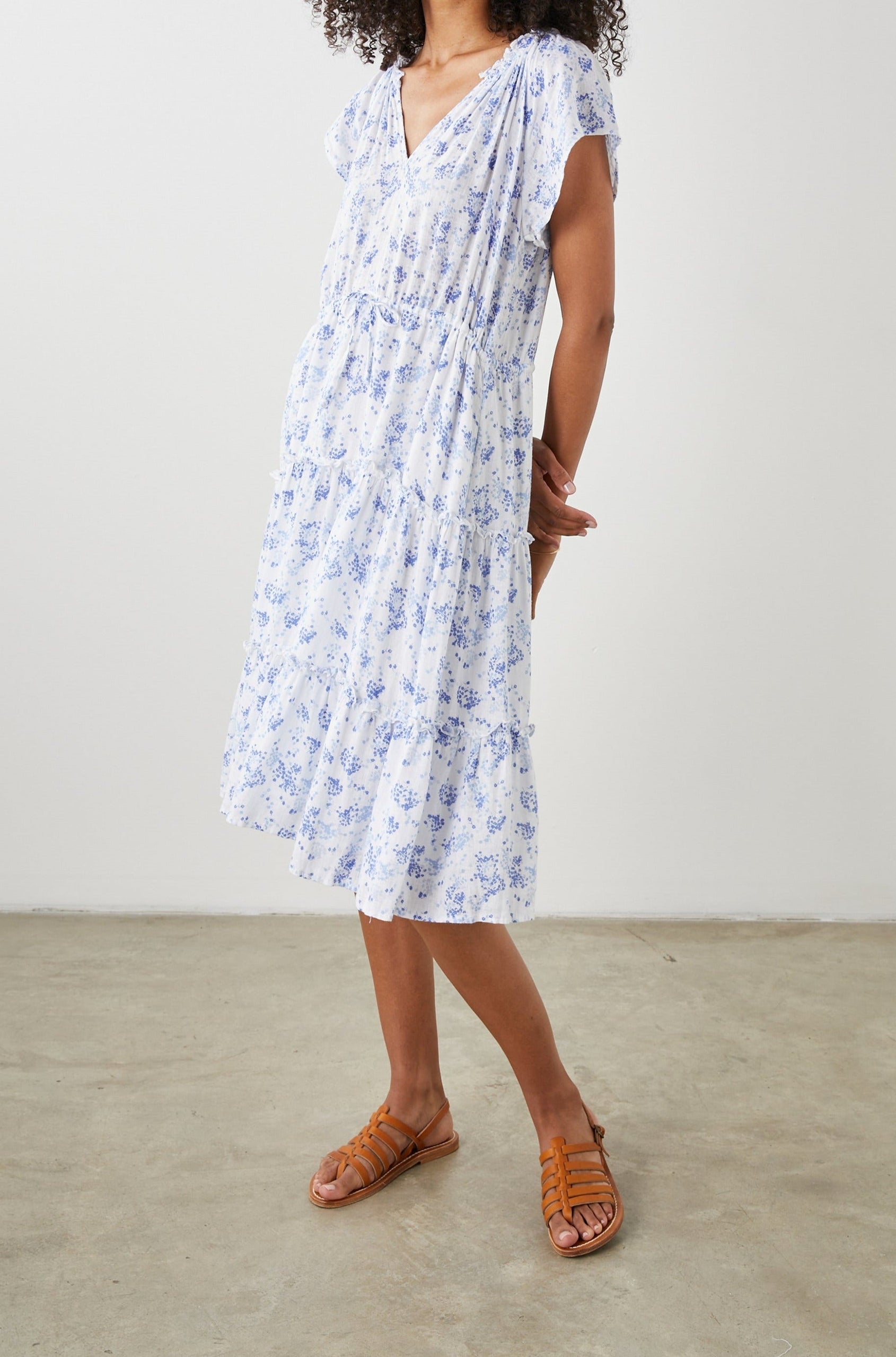 Juni Short Sleeve Midi Dress with a V Neck, Light Ruching along the Neckline, a Drawstring Waist, and a Tiered Skirt in Blue Blossoms Colorway, on White - Side Full Body View Featured on Model