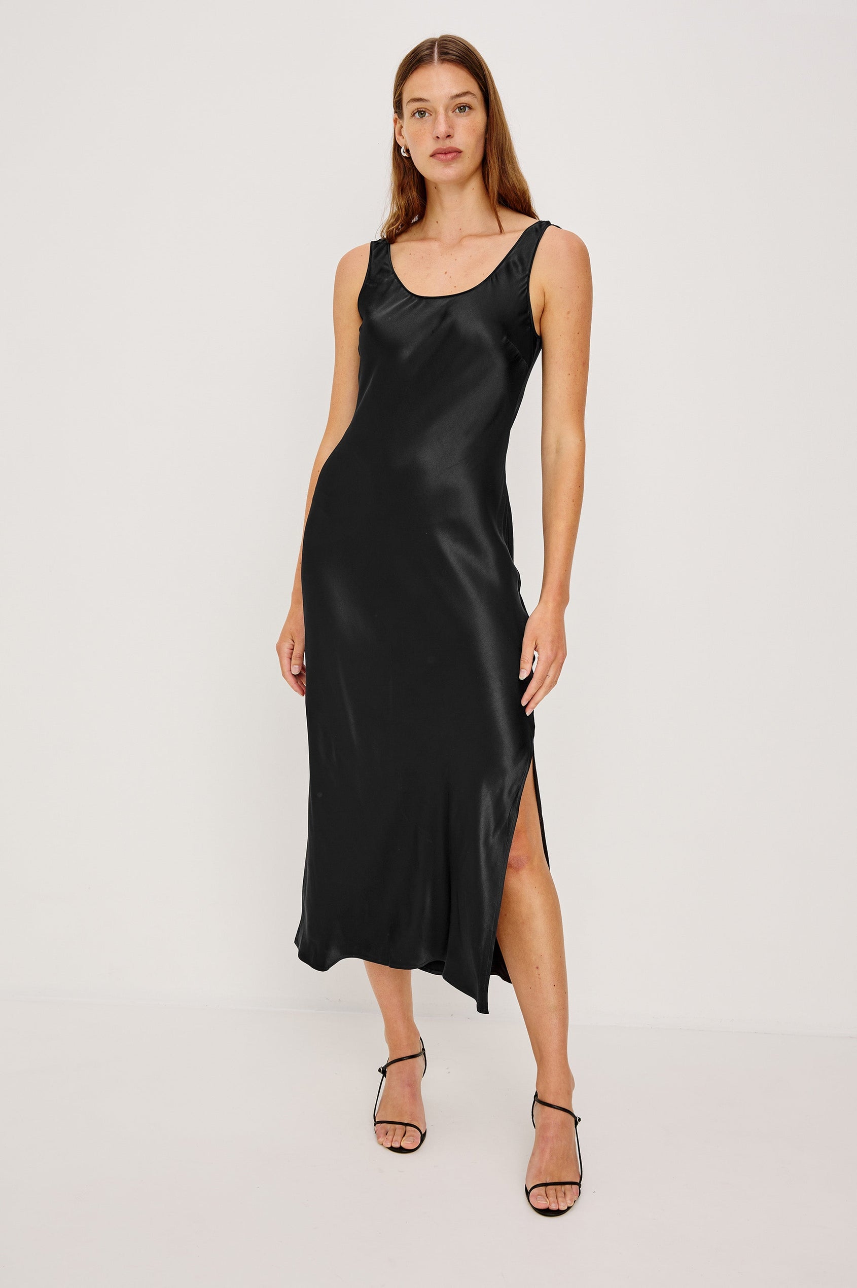 Kailani Sleeveless Midi Dress with Shoulder Straps, a Scoop Neck and Side Slit to the Knee in Black Satin Crepe Colorway - Front Full Body View Featured on Model