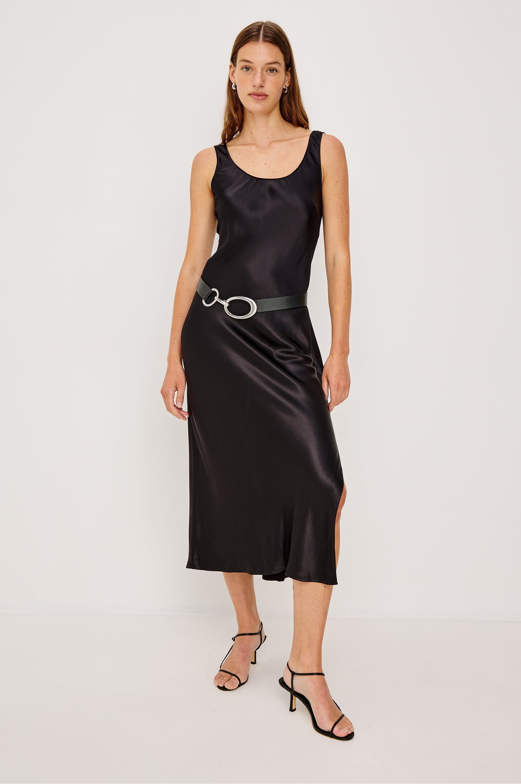 Kailani Sleeveless Midi Dress with Shoulder Straps, a Scoop Neck and Side Slit to the Knee in Black Satin Crepe Colorway - Front Full Body View Featured on Model, Styled with belt