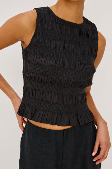 Kane Sleeveless Fitted Top in Cotton With Diamond Smocking All Over, High Boat Neckline, and Flared Ruffle Hem in Black Colorway - Upper Body Close Up Front View Featured on Model