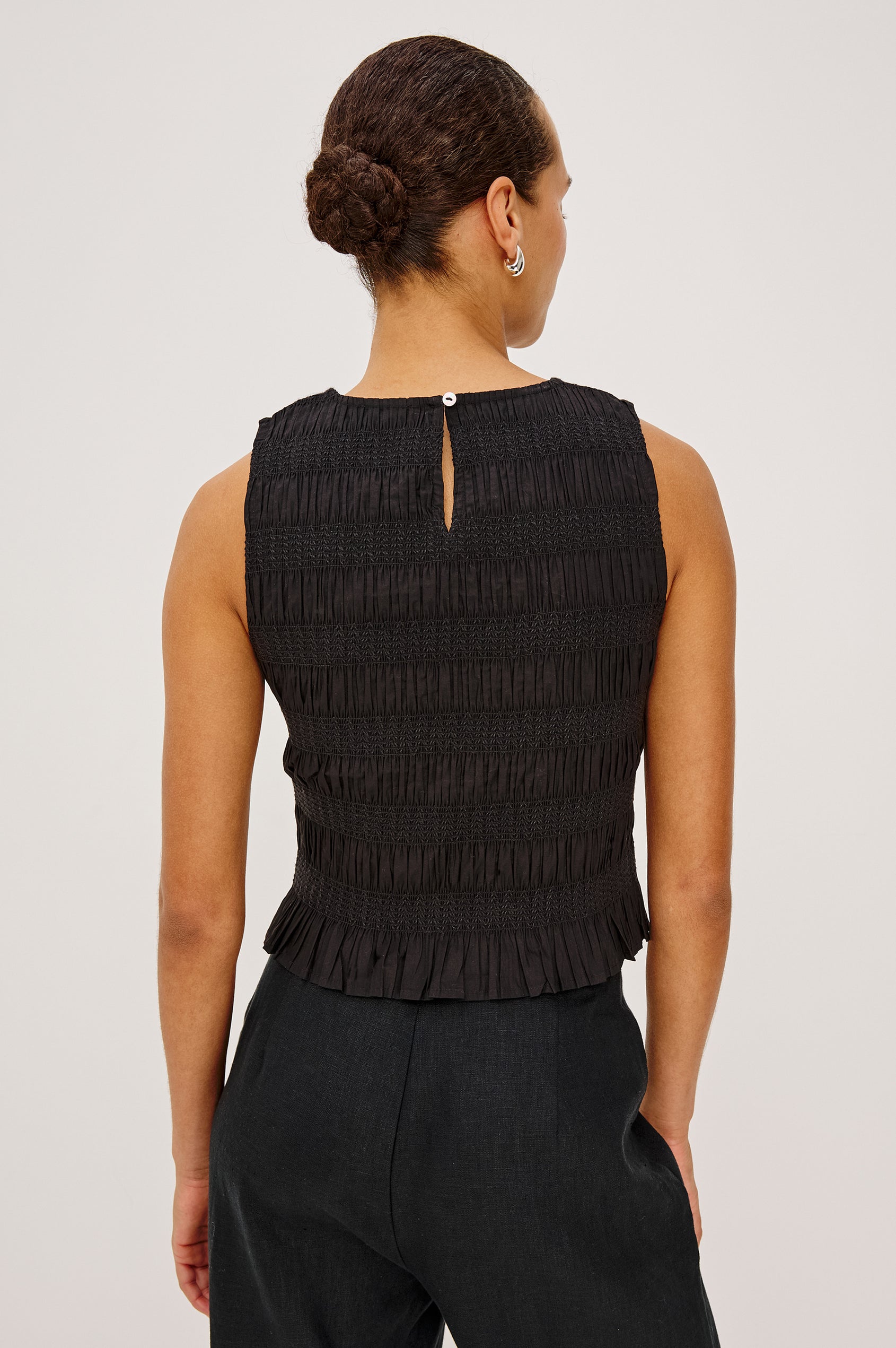Kane Sleeveless Fitted Top in Cotton With Diamond Smocking All Over, High Boat Neckline, and Flared Ruffle Hem in Black Colorway - Upper Body Back View Featured on Model