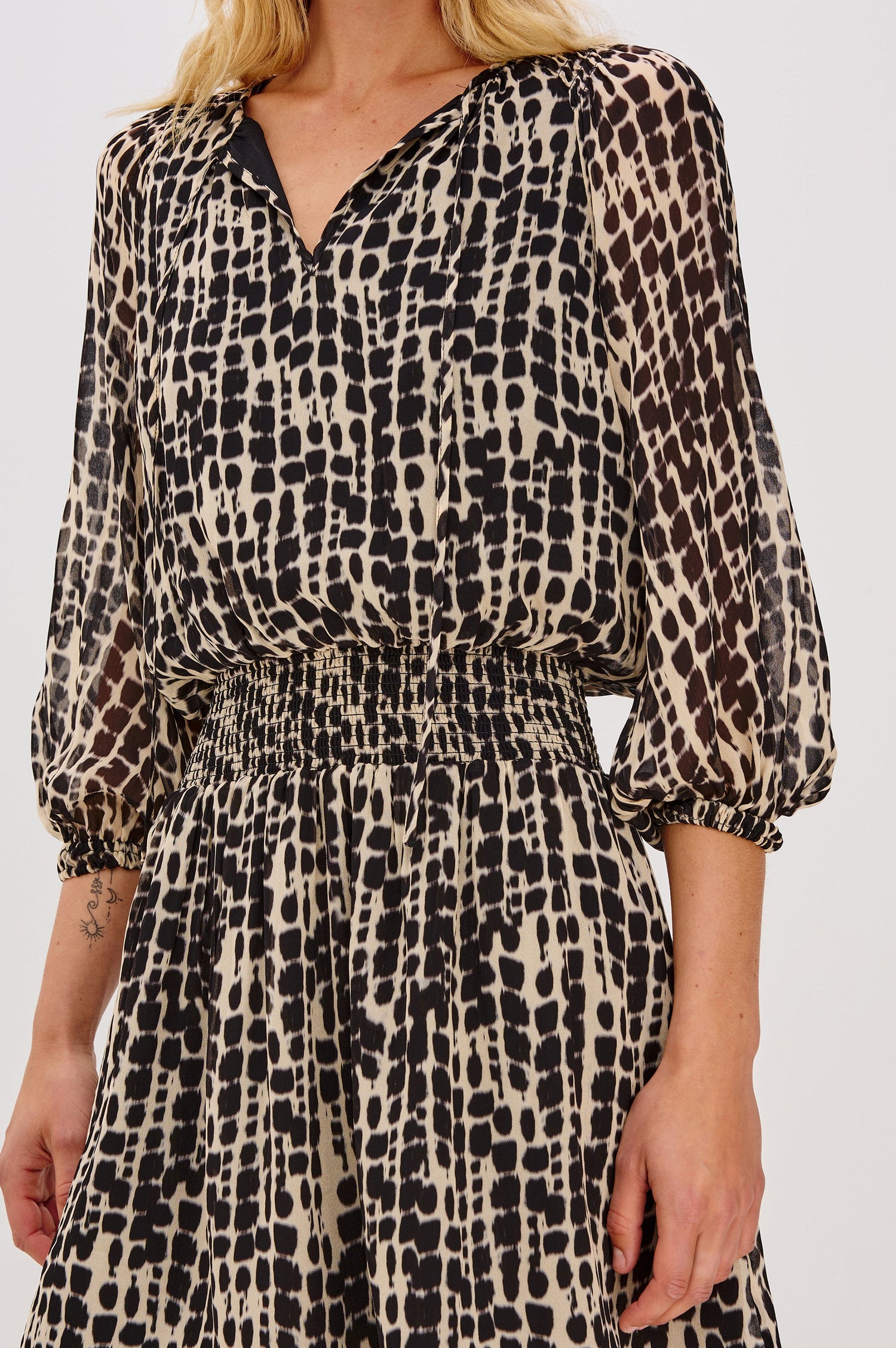 Printed dress with a tiered skirt and smocked detailing at the shoulders and waist. The dress includes a front tie closure for an adjustable neckline. Close Up View on Model.