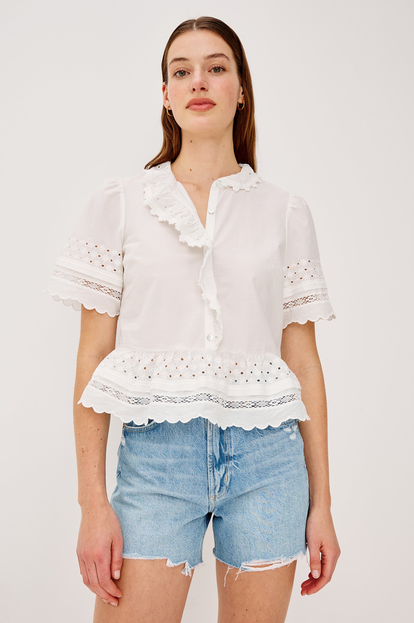Keeta Shirt in Lightweight Beach Cotton With Ruffled Peter Pan Collar Front Placket Short Sleeves Tiered Hem Crochet Eyelet and Scalloped Trim in White Colorway - Upper Body Front View Featured on Model