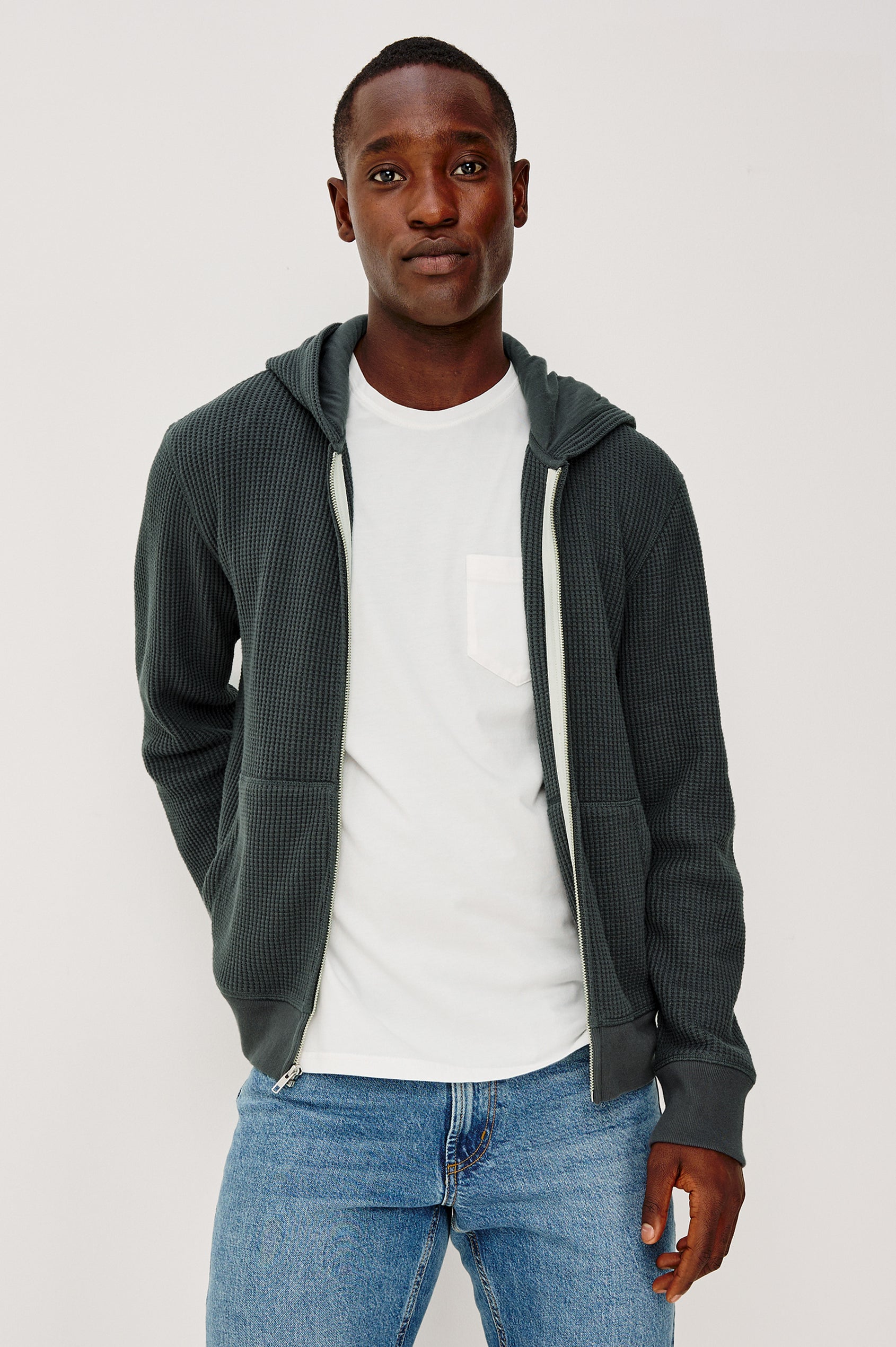 Kenton is a zip front hooded sweatshirt with front patch pockets and ribbed cuffs in Ink colorway. Front view featured on model.