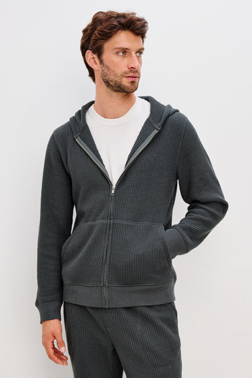 Kenton is a zip front hooded sweatshirt with front patch pockets and ribbed cuffs in Ink colorway. Front view featured on model.