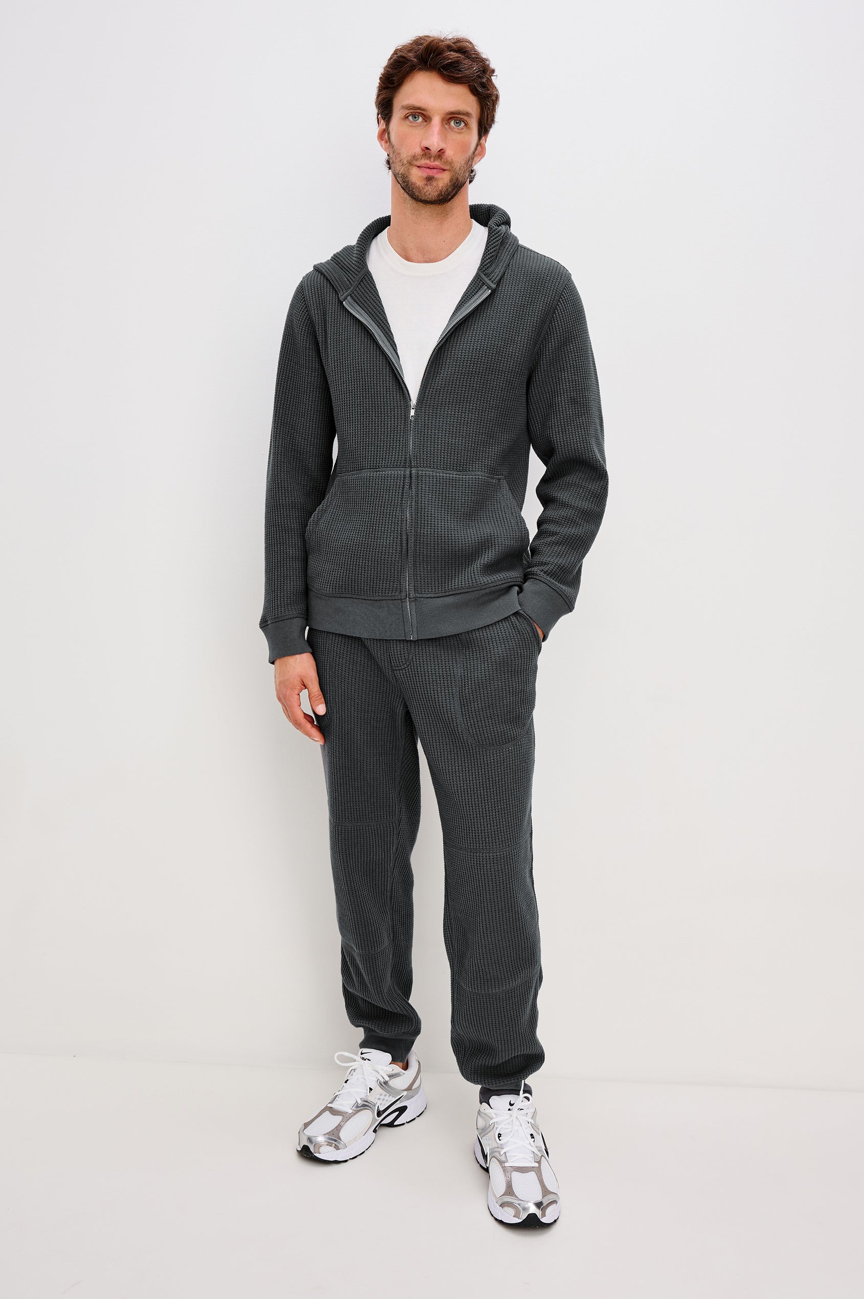 Kenton is a zip front hooded sweatshirt with front patch pockets and ribbed cuffs in Ink colorway. Front full body view featured on model.