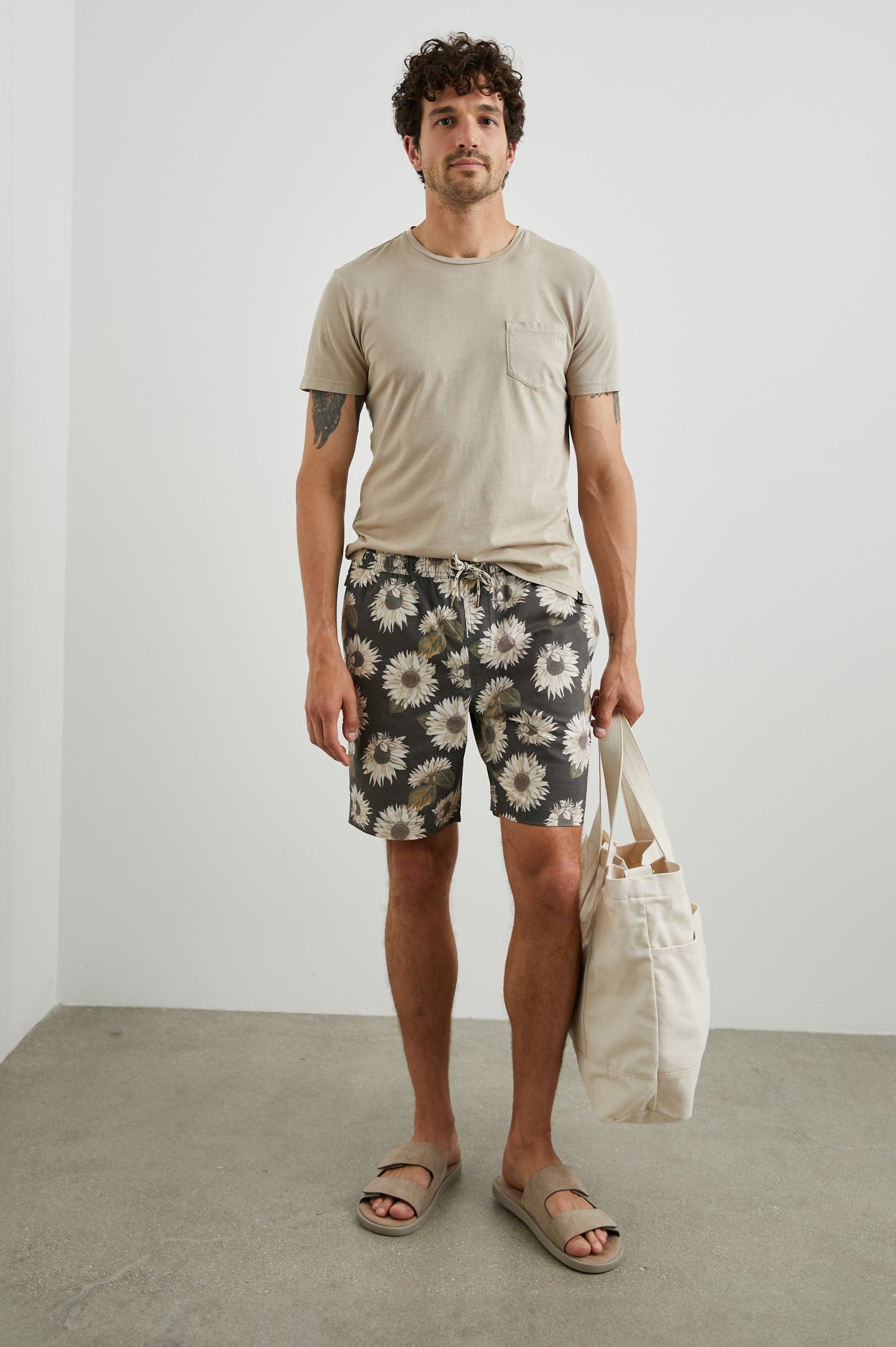 Kian Swim Shorts with an Elastic Drawstring Waistband, Two Front Pockets and a Back Button Flap Pocket in Sunflower Twirl Black Colorway, Sunflowers on Black - Front Full Body View Featured on Model