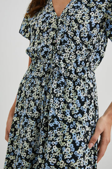 Kiki Short Sleeve Midi Dress with a V Neck, Buttons Down the Front Bodice, a Drawstring Waist and Ruffles at the Hem in Midnight Meadow Floral Colorway, Blue and Cream Flowers on Black - Front View Featured on Model 