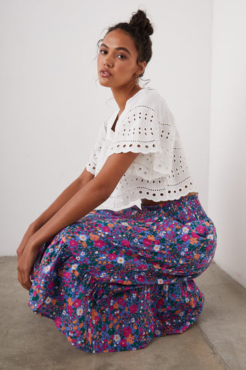 Kit Short Sleeve Crop Top with a Square Neckline, Front Button Closure, and an Eyelet Design in White Eyelet Embroidery Colorway - Front Full Body View Featured on Seated Model 