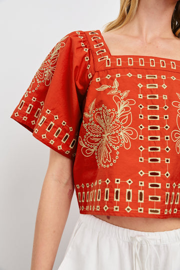 Laine airy cotton poplin top with wide short sleeves and a loose fit. Contrast eyelet embroidery in color Terracotta - close up of details on model