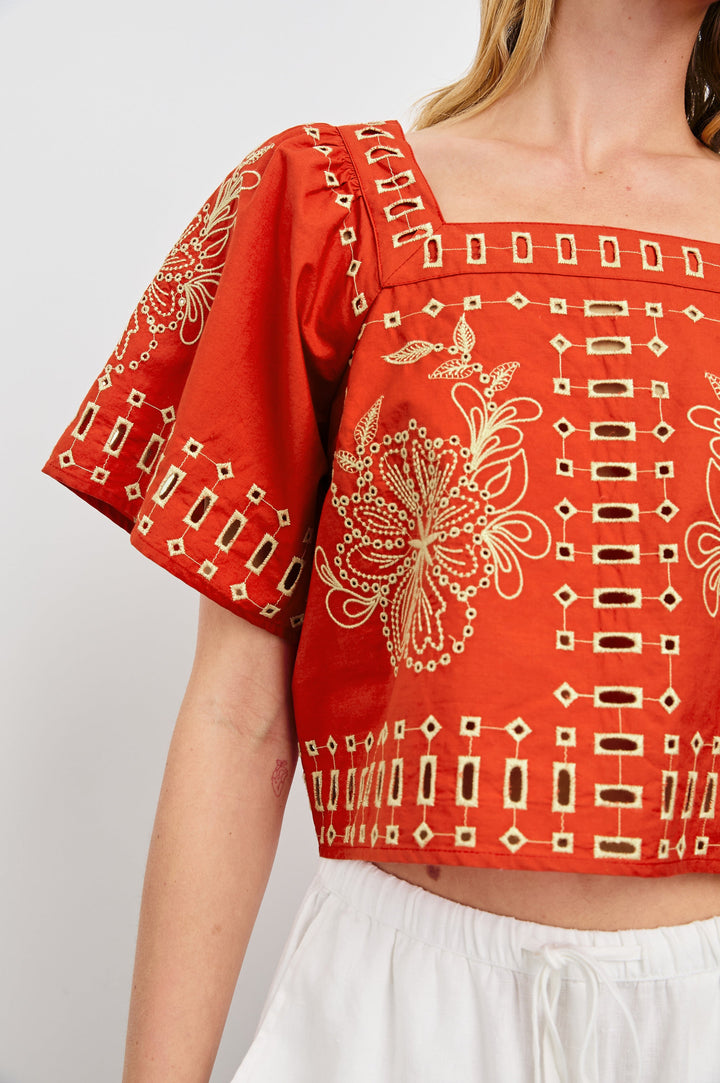 Laine airy cotton poplin top with wide short sleeves and a loose fit. Contrast eyelet embroidery in color Terracotta - close up of details on model