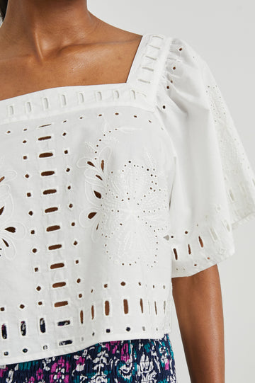 Laine Short Sleeve Crop Top with Square Neckline, and a Floral and Geometric Eyelet Design in White Colorway - Front View Featured on Model