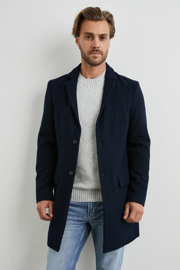 Lark Thigh-Length Coat with Two Button Closure, Notched Lapels, and Two Front Flap Pockets in Navy Colorway - Front View Featured on Model