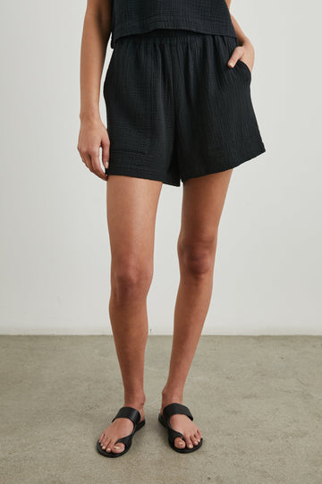 Leighton Shorts with Textured Fabric, a Smocked Elastic Waist, and Large Front Pockets in Black Colorway - Front View Featured on Model