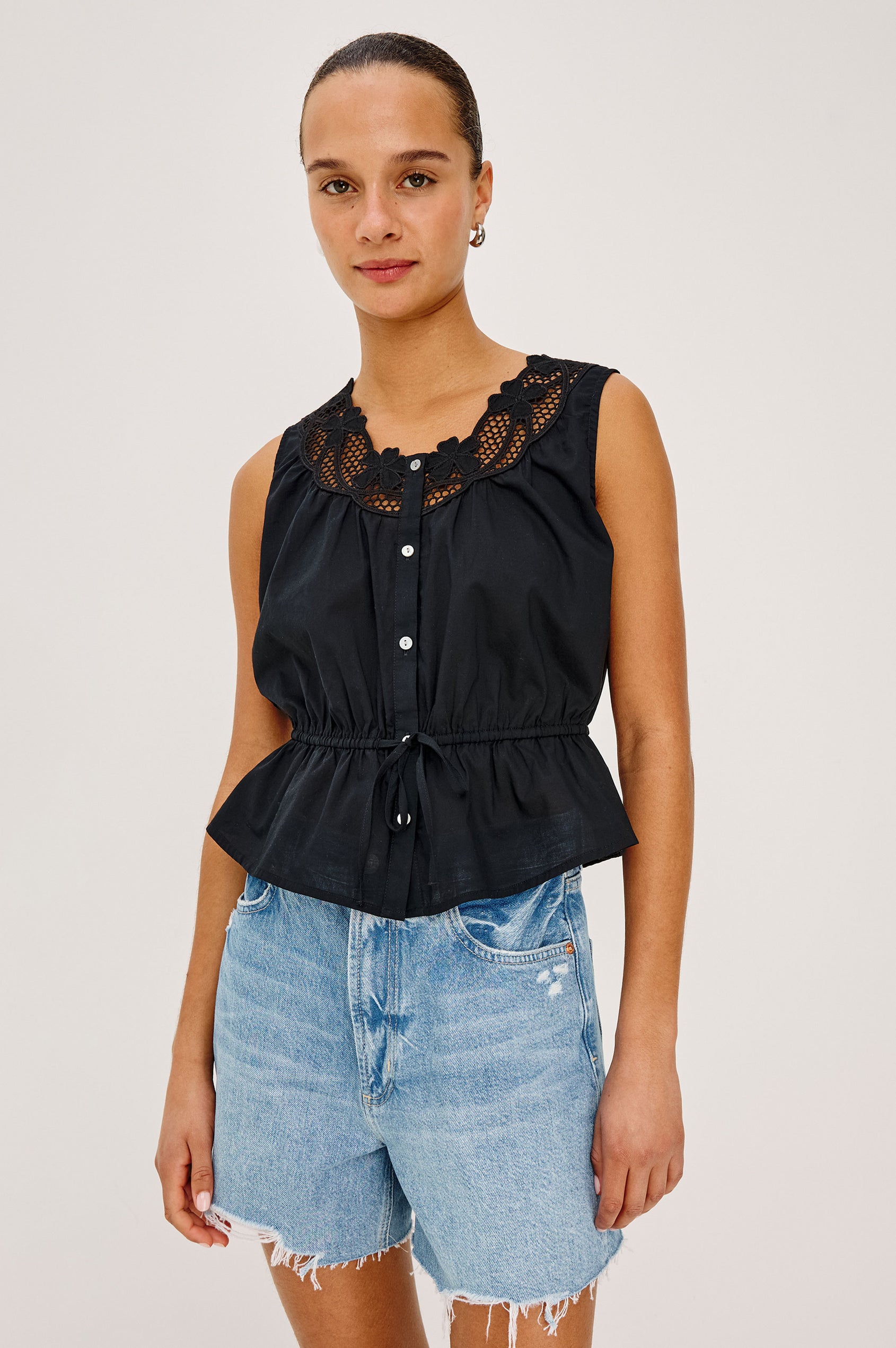 Leilani Top in Lightweight Beach Cotton With Scoop Neckline, Lattice Embroidery, Front Buttons, Relaxed Fit, and Adjustable Waist Ties in Black Colorway - Upper Body Front View Featured on Model