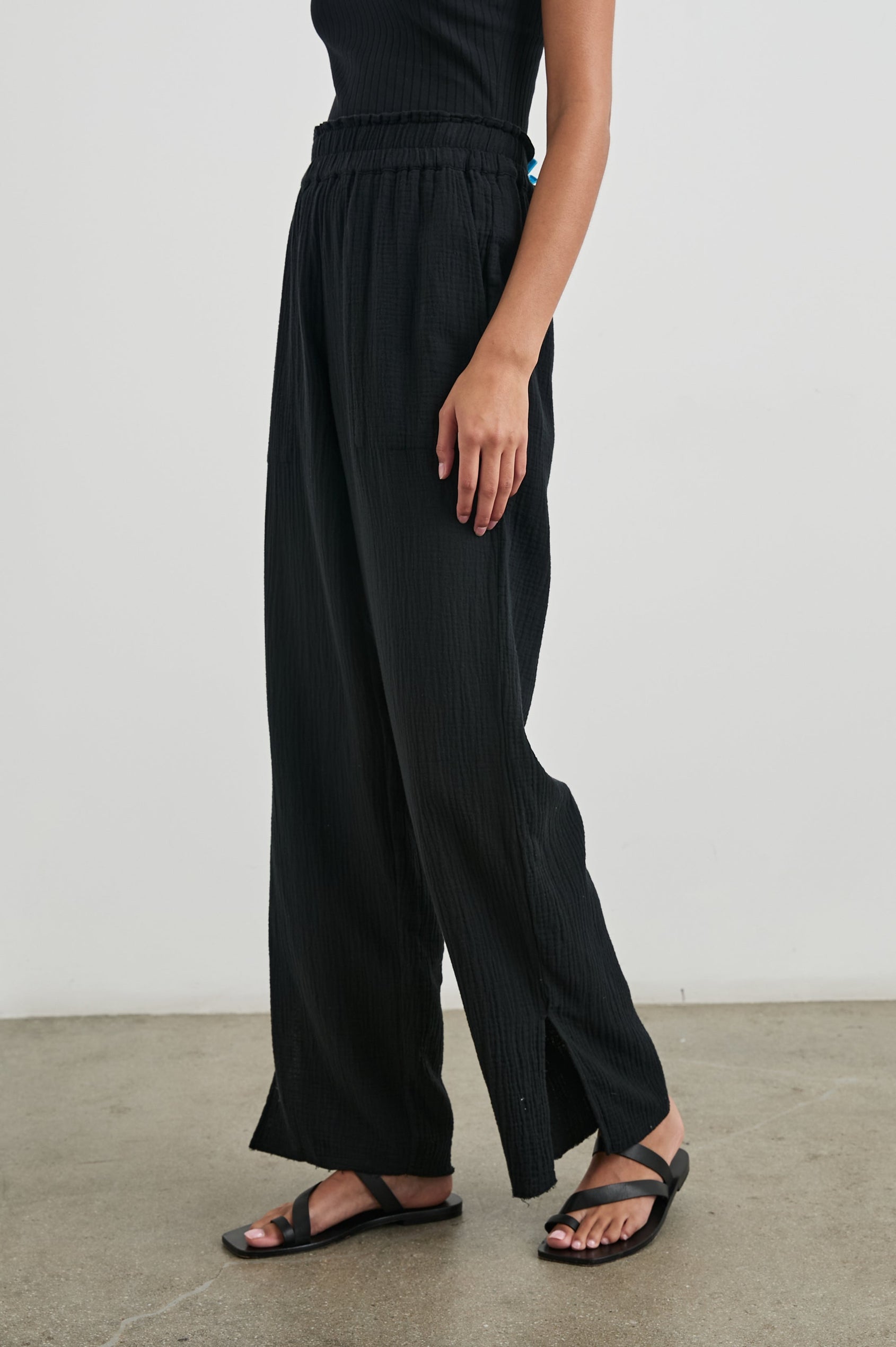 Leon Pant with a Smocked Waistband, Short Side Slits on Outer Leg and Two Front Seam Pockets in Black Colorway - Side View Featured on Model