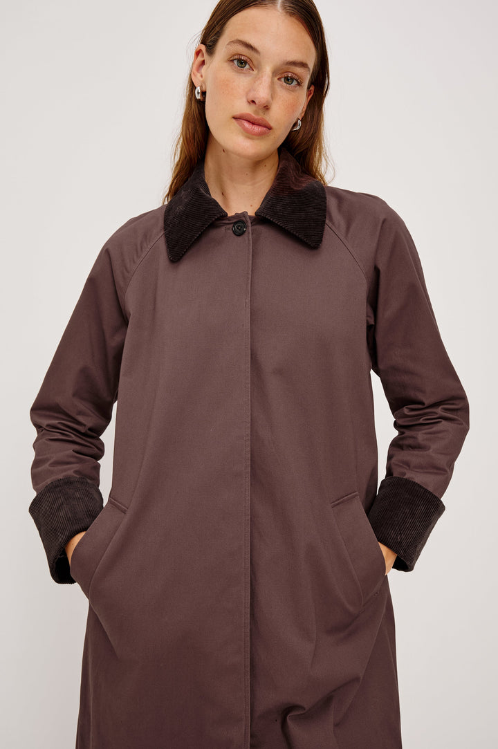 Full-length coat with a classic silhouette in Raisin Colorway. The coat is fully lined in plaid and finished with corduroy accents at the cuffs and collar for a heritage-inspired look. Close Up View featured on Model.