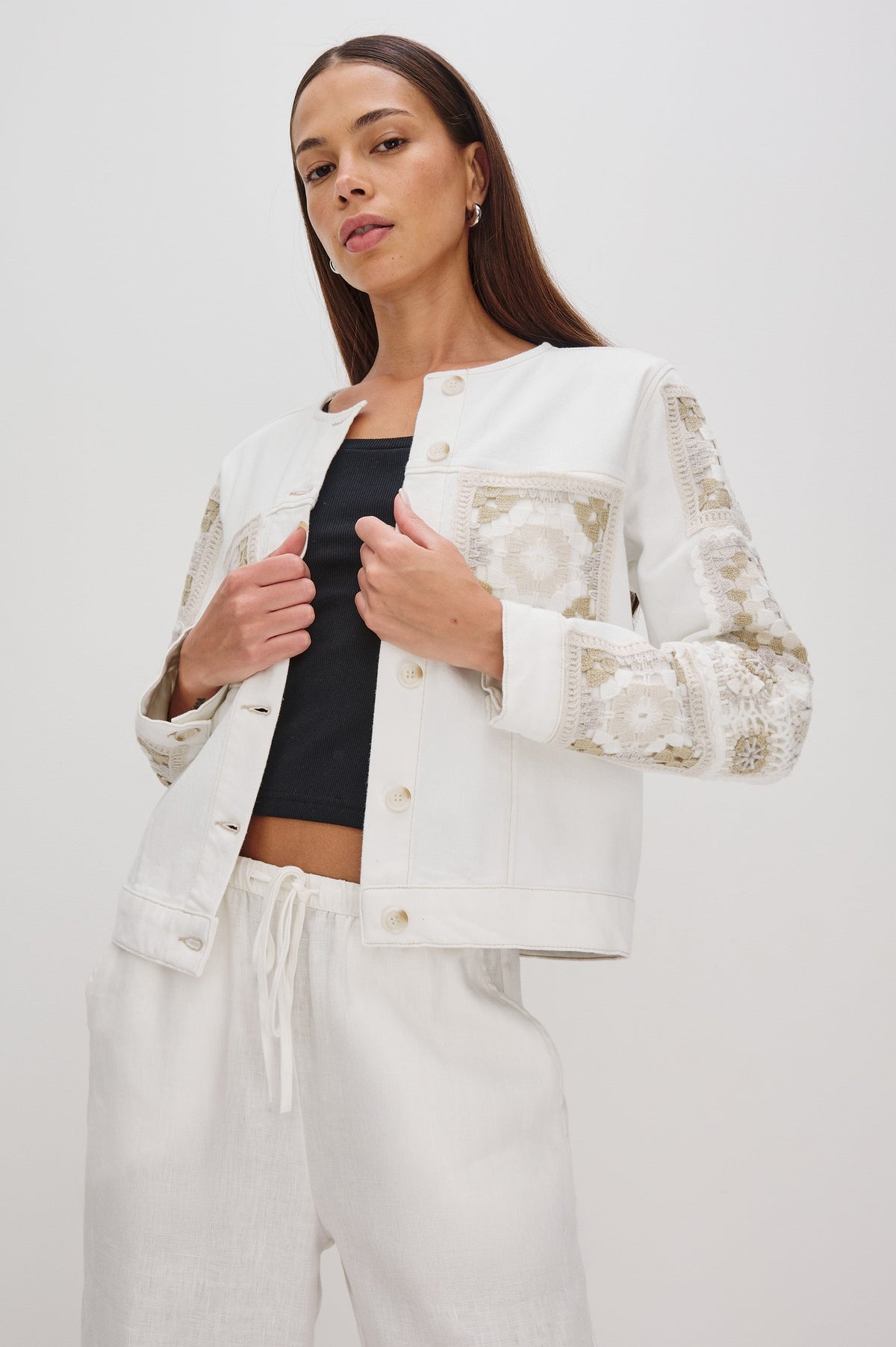 Lido collarless denim jacket with contrast embroidery details, chest pockets and embellishment buttons in vintage ecru crochet colorway. Front view on model.