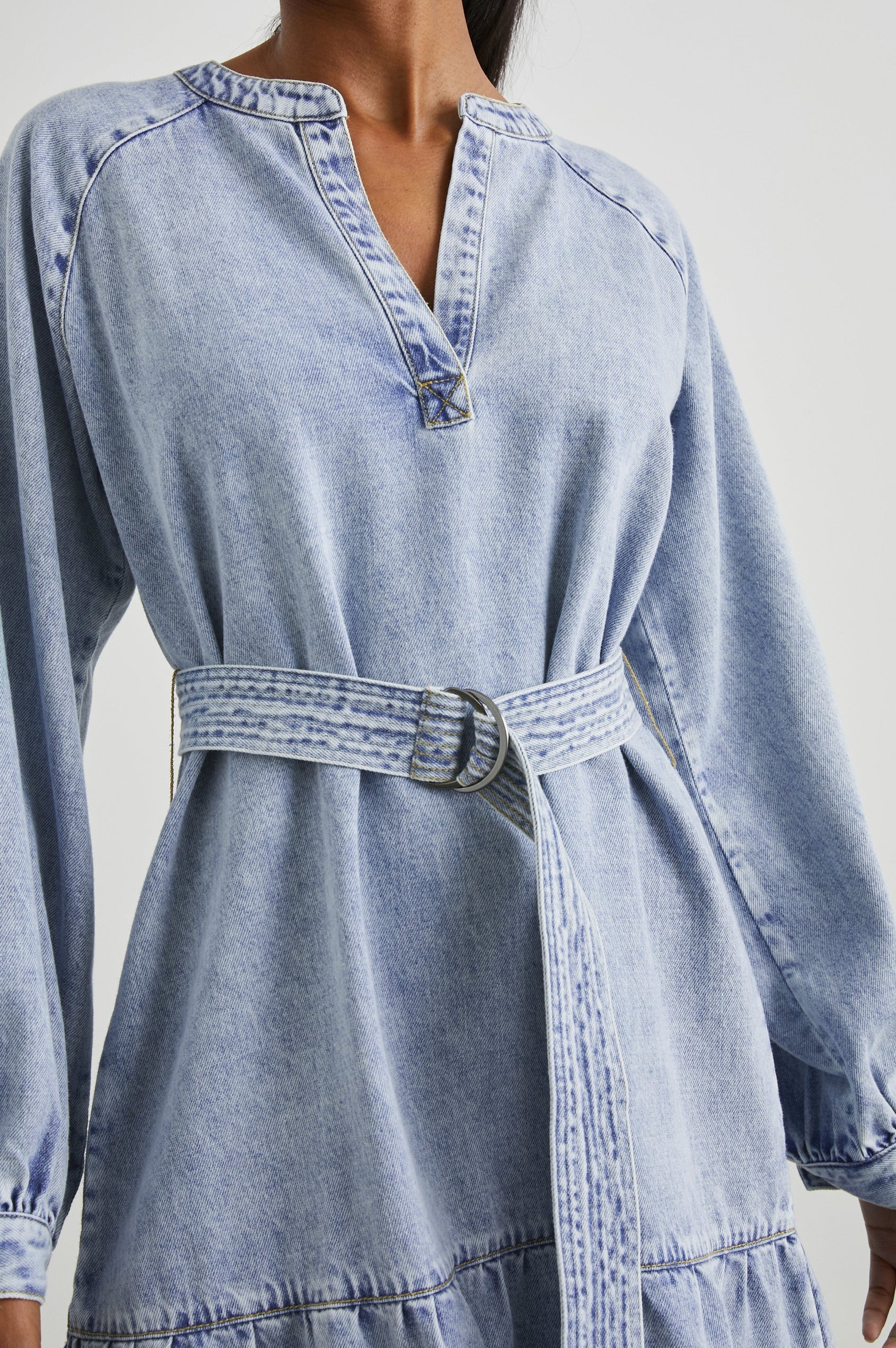 Lila Long-Sleeve Denim Mini Dress with a Fabric Double Ring Belt, a V Neck and Snap Cuffs in Faded Indigo Colorway - Front View Featured on Model 