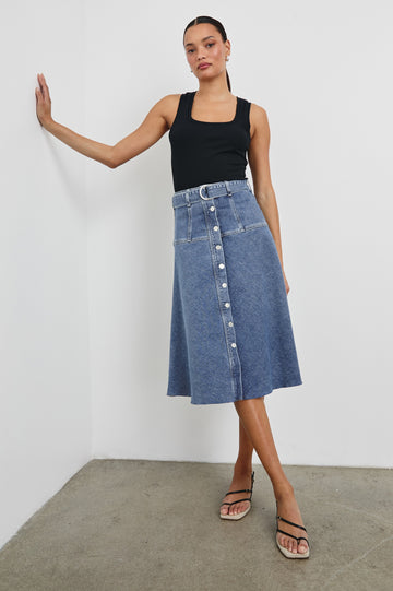 Loma Below-Knee A-Line Denim Skirt with an Exposed Button Front Opening, Adjustable Self Belt with D-Ring Closure and a Raw Hem in Pacific Coast Colorway. Full Body Front View Shown on Model.