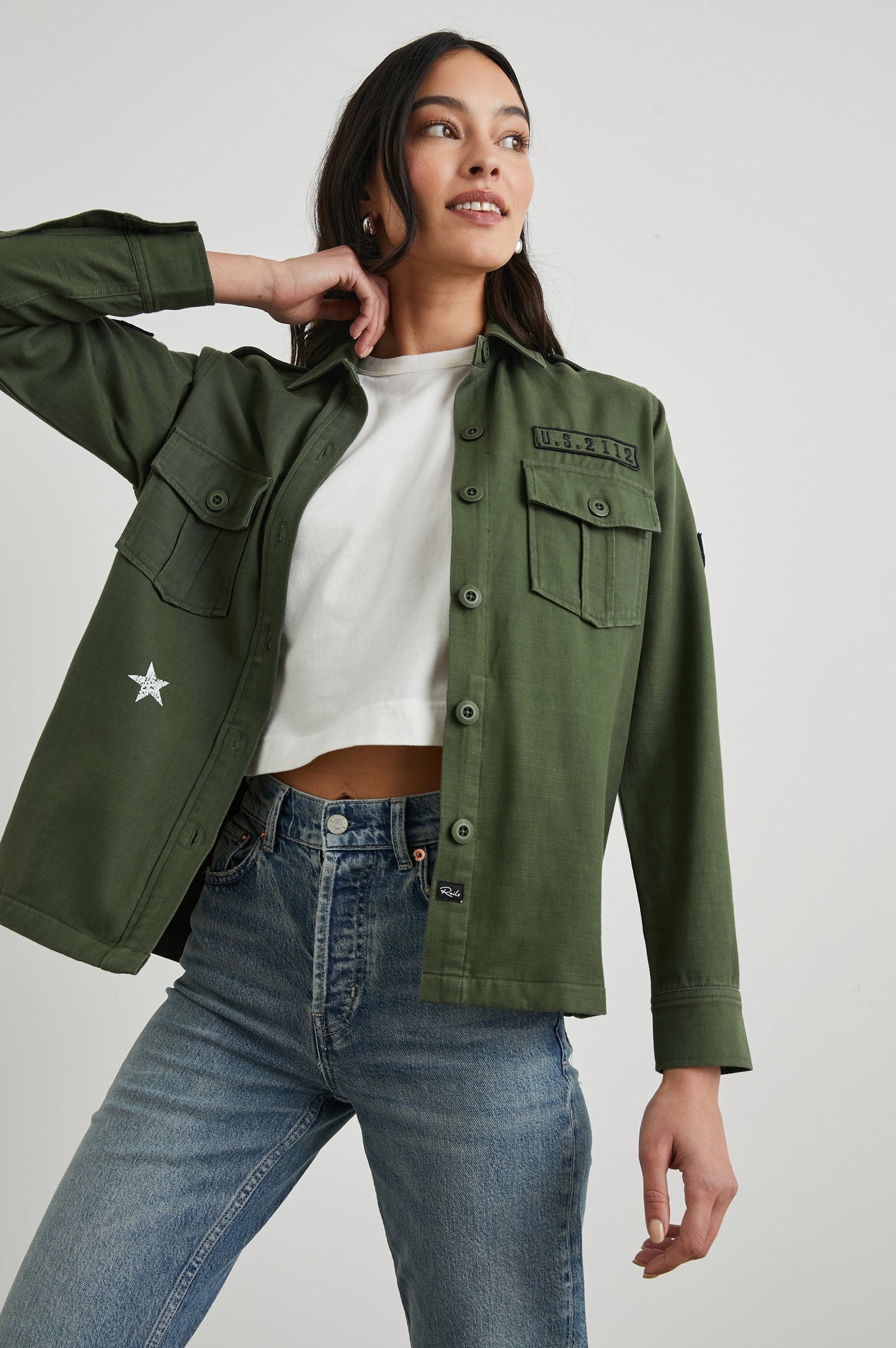 Loren Long-Sleeve Shirt Jacket with Button Closure, Two Chest Button Flap Pockets, a Military Patch on Each Arm, a Military Number above One Chest Pocket, and Button Shoulder Tabs in Military Olive Colorway, with White Stars - Front View Featured on Model
