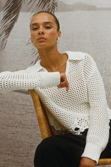 Louise open knit crochet sweater in Ivory with solid knit collar and floral scalloped hem - on model sitting on chair