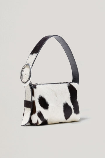 The Lucca is a long-hair cowhide shoulder bag with an adjustable strap and polished silver oval buckle. In Cowgirl Haircalf colorway. Front view featured.