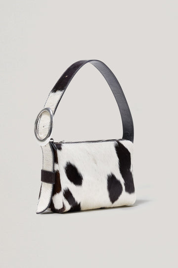 The Lucca is a long-hair cowhide shoulder bag with an adjustable strap and polished silver oval buckle. In Cowgirl Haircalf colorway. Front view featured.