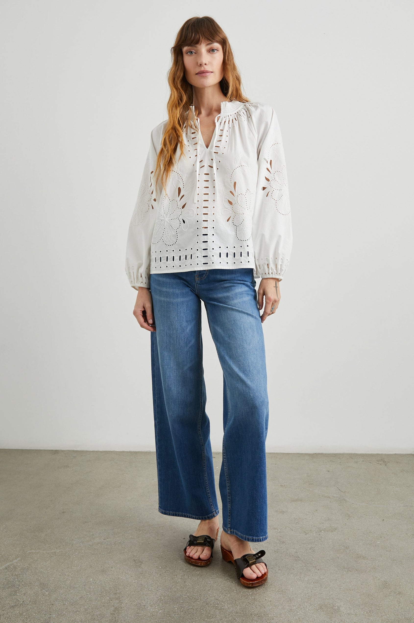 Lucinda Long-Sleeve Top with Billowy Sleeves, a V Neck with a Drawstring Collar, and a Floral and Geometric Eyelet Design in White Colorway - Front Full Body View Featured on Model  