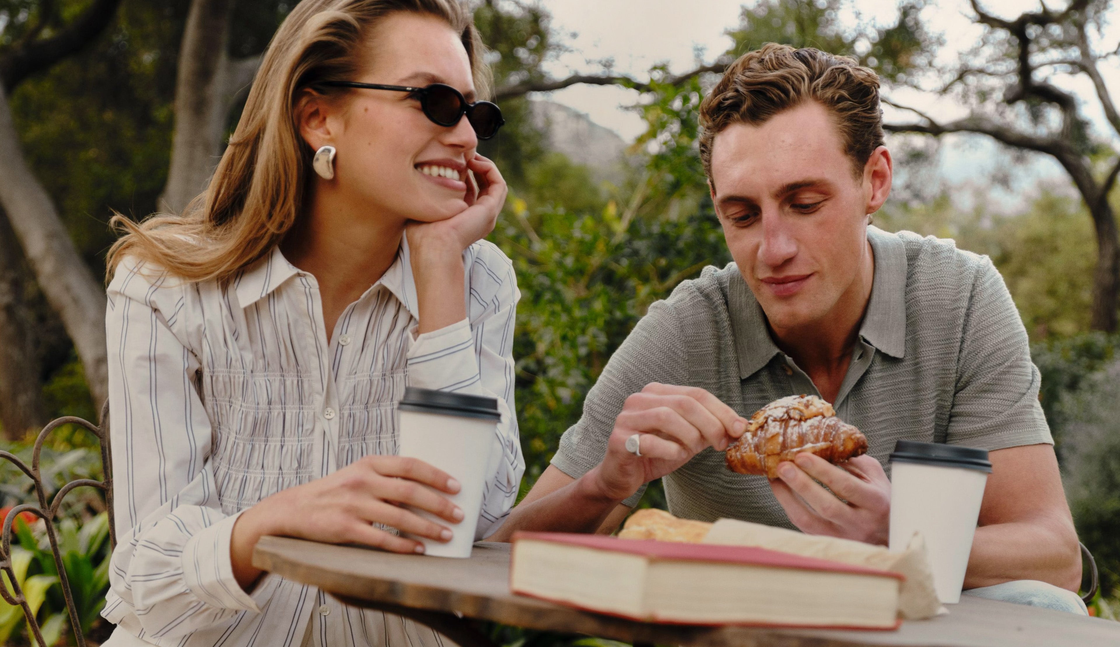 Man and Woman sitting at a coffee table drinking coffee and eating pastries