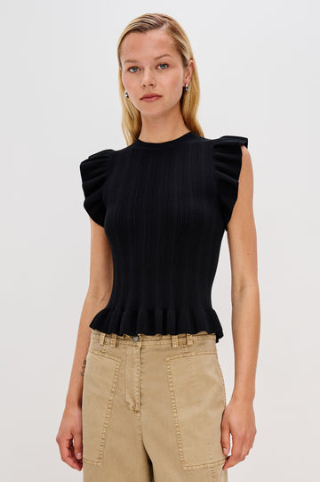 Marci is a short-sleeve fine-gauge knit sweater top. The fitted silhouette is accented with flutter sleeves and a ruffled hem in Black Colorway - Front View Featured on Model