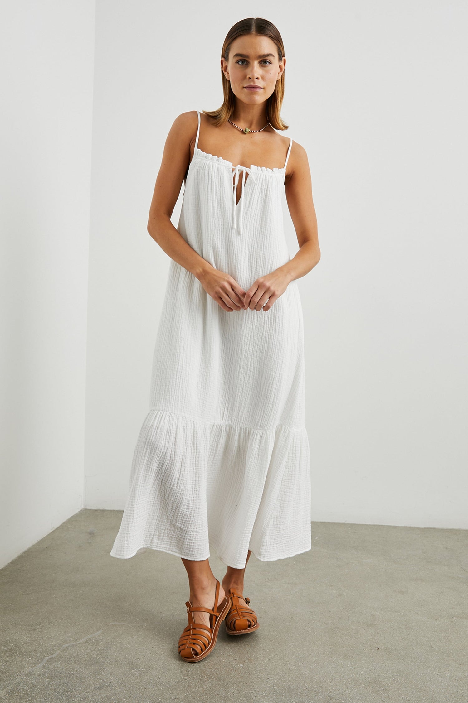 Marseille Midi Dress with Adjustable Spaghetti Straps, a Deep V Neck with a Tie, and a Lightly Ruffled Hem in White Colorway - Front Full Body View Featured on Model