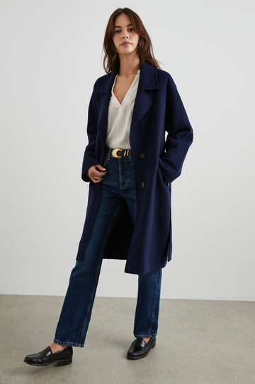 Marta Knee-Length Coat with Two Button Closure, Notched Lapels, Two Front Flap Pockets, and a Tie Belt in Navy Colorway - Front Full Body View Featured on Model 