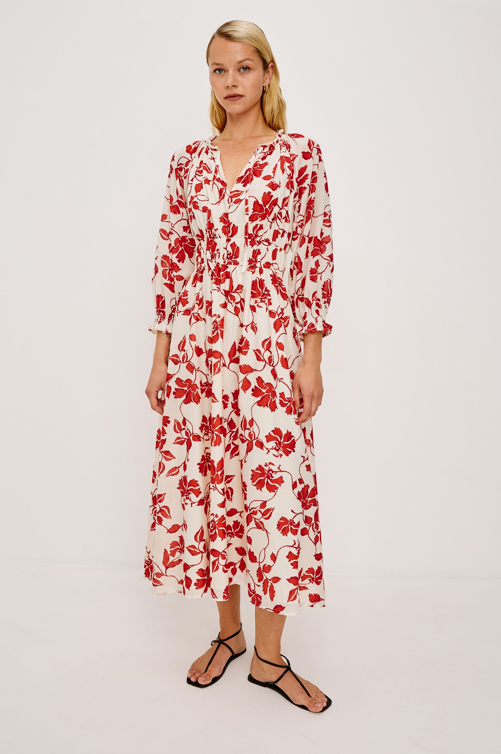 Matia Maxi Dress in Cotton With Banded Ruffle V-Neckline With Self-Ties Elastic Waist and Long Raglan Puff Sleeves in Red Jasmine Colorway - Full Body Front View Featured on Model