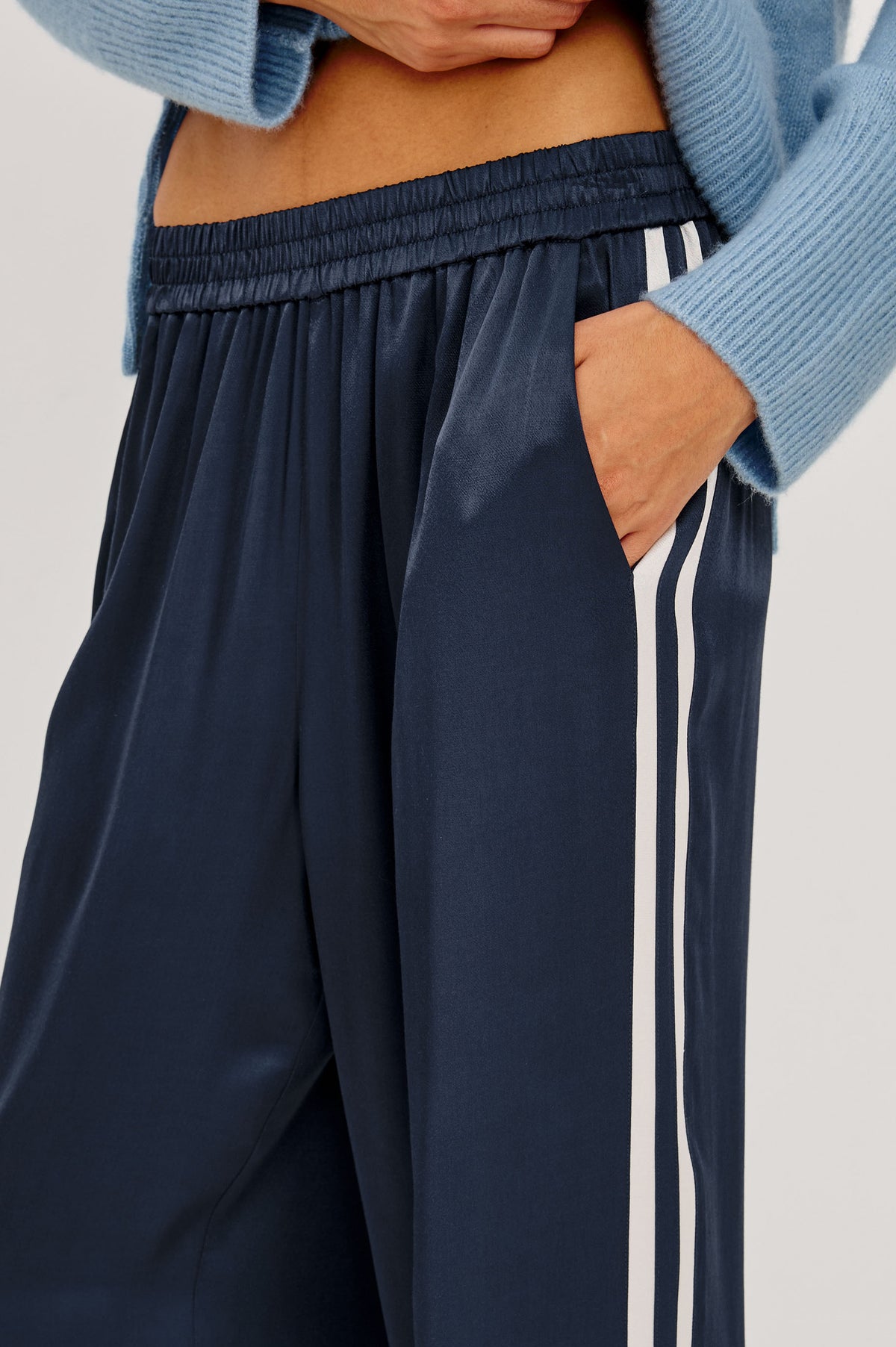 Merida Track Pant in Satin-Back Crepe With Elastic Waist, Side Slant Pockets, Wide Legs, and Contrast Side Stripes in Navy Colorway - Side Crop Detail View Featured on Model.