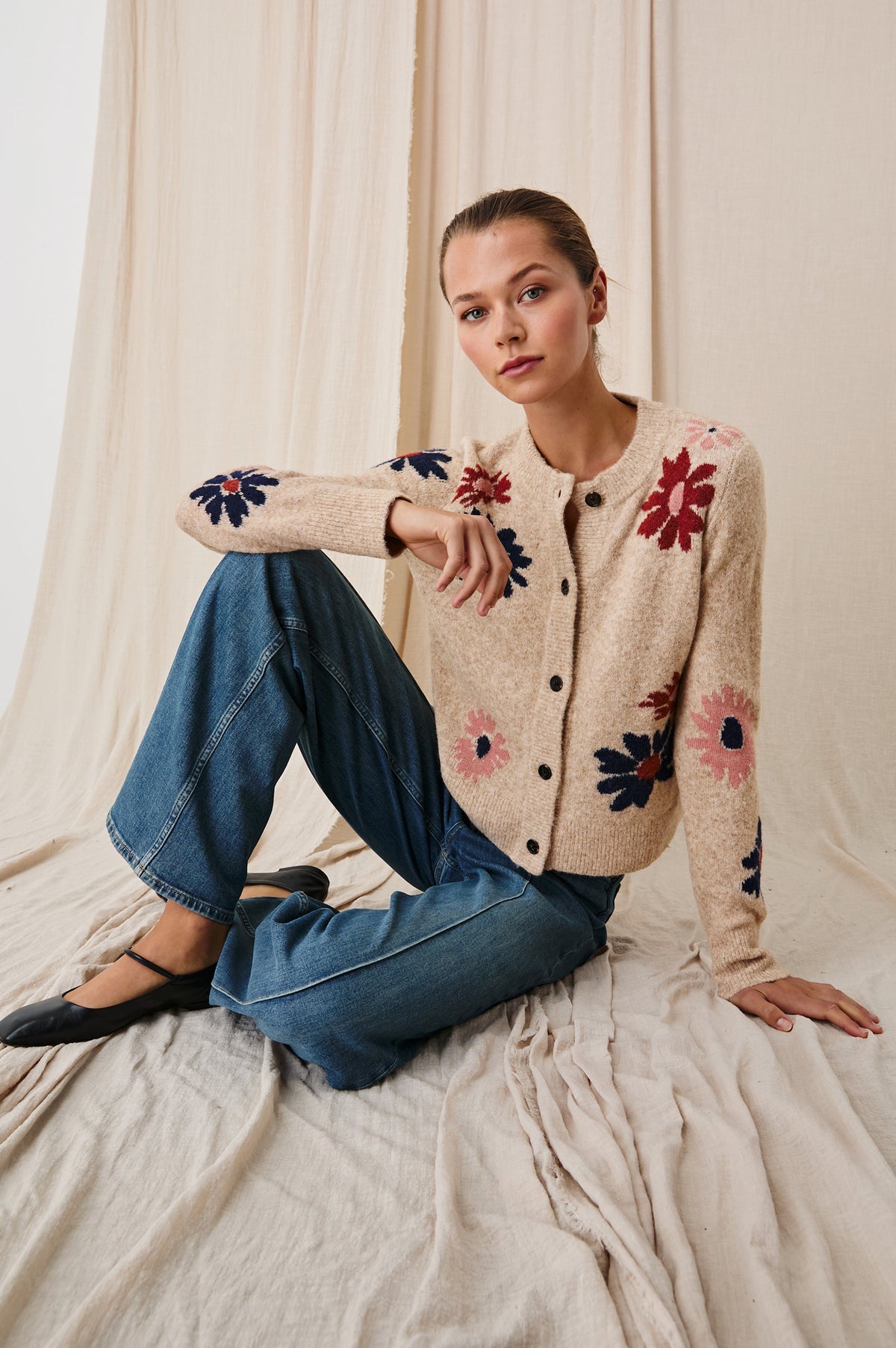 Millie Long-Sleeve Sweater with Front Button Closure, a Crew Neck and Ribbed Trim in Mauve Meadow Colorway, Flowers in Pink, Navy and Red on Oatmeal - Front Full Body View Featured on Seated Model 