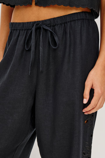 Made from midweight linen the Mirina Pant has an elastic waistband with adjustable center front ties side pockets loose straight legs and intricate floral cutwork and scalloped trim.