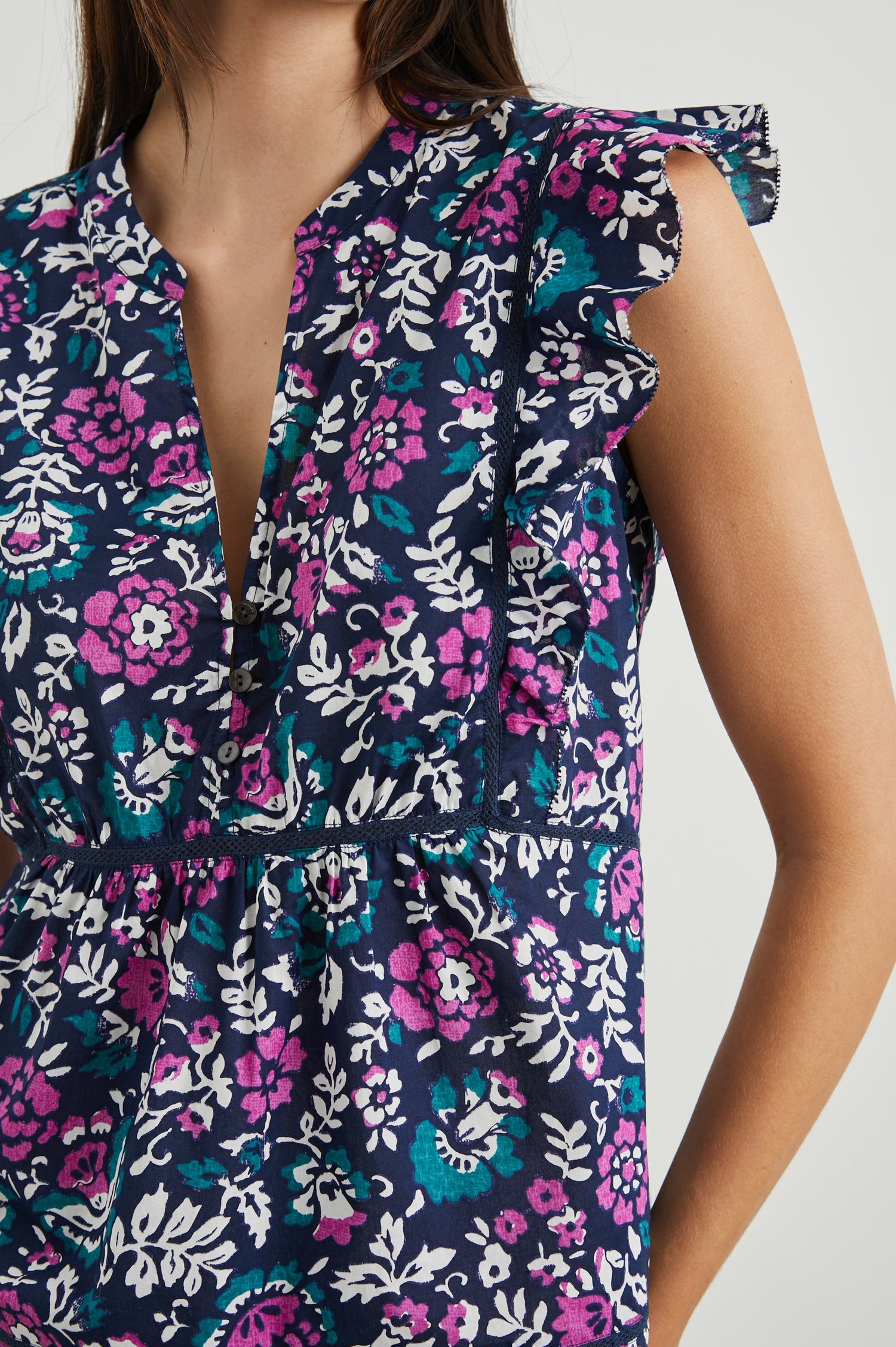Misha Short Sleeve Top with Flutter Sleeves, a Deep V Neck, and Vertical and Horizontal Black Seams in Woodblock Floral Colorway, Pink, White and Green on Navy - Front View Featured on Model 