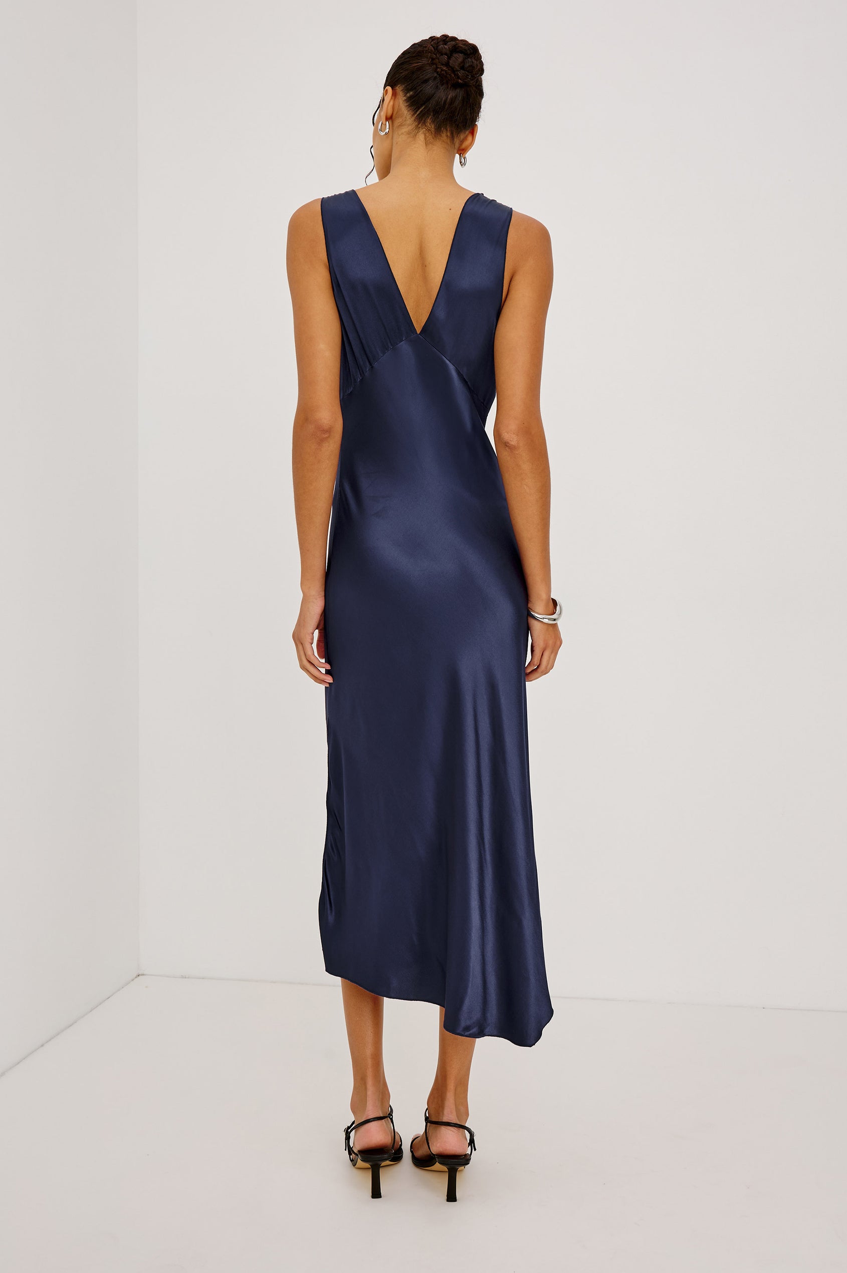 Monique Midi Bias Cut Slip Dress in Satin-Back Crepe With V-Neckline, Asymmetric Hem, and Side Slit in Navy Colorway - Full Body Back View Featured on Model