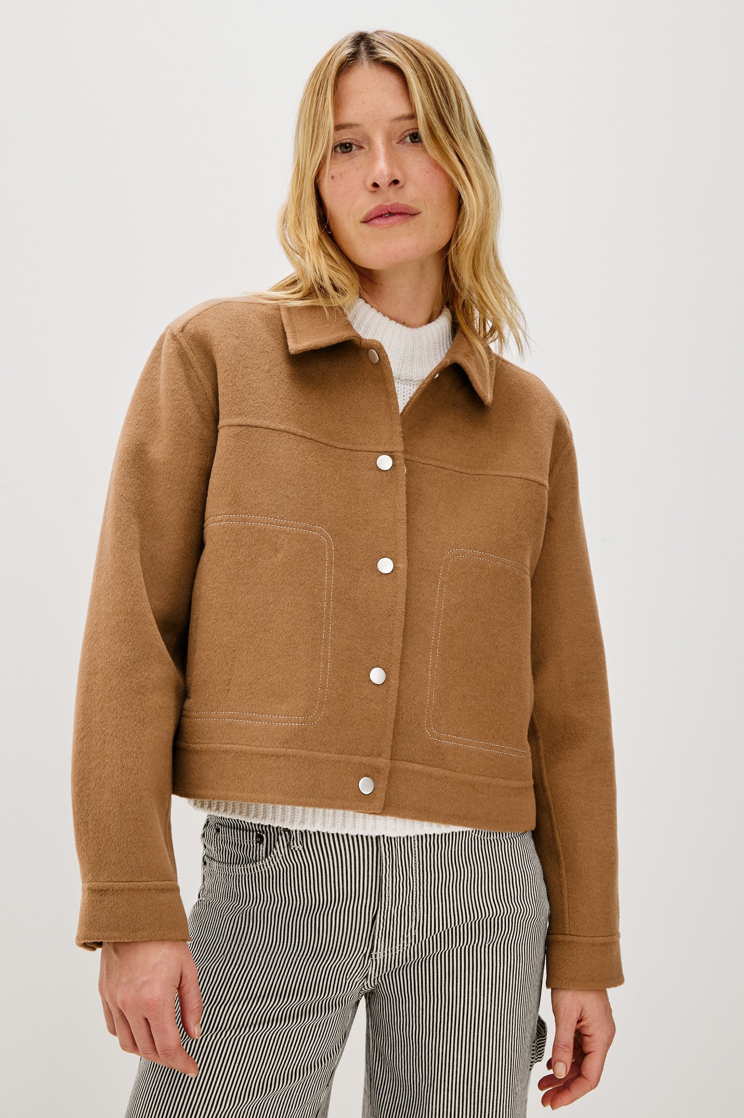 The Mountain jacket is cropped and collared with a snap front and side pockets in Camel colorway. Front view featured on model.
