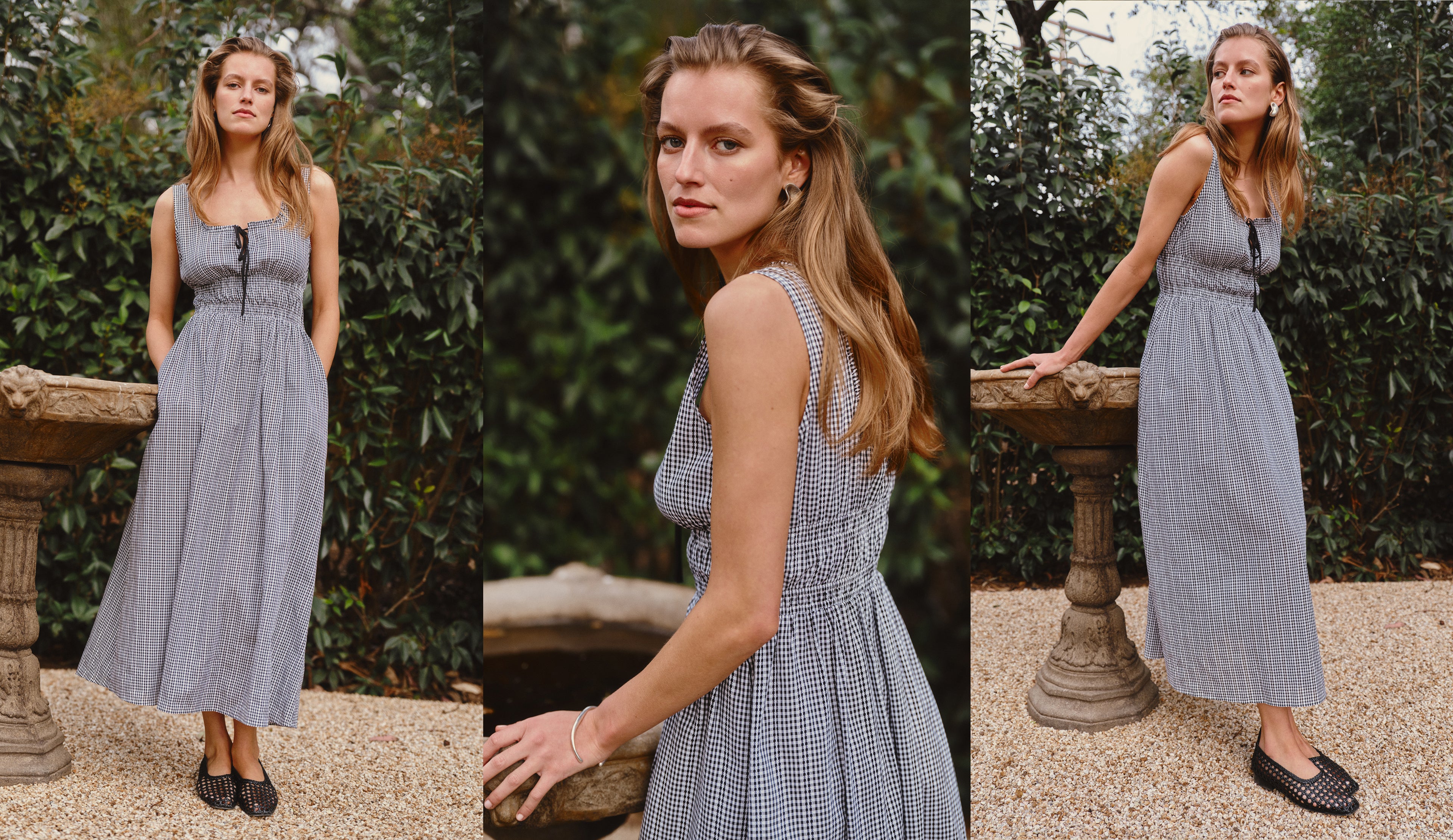 Woman wearing a black checkered dress standing outdoors with greenery in the background