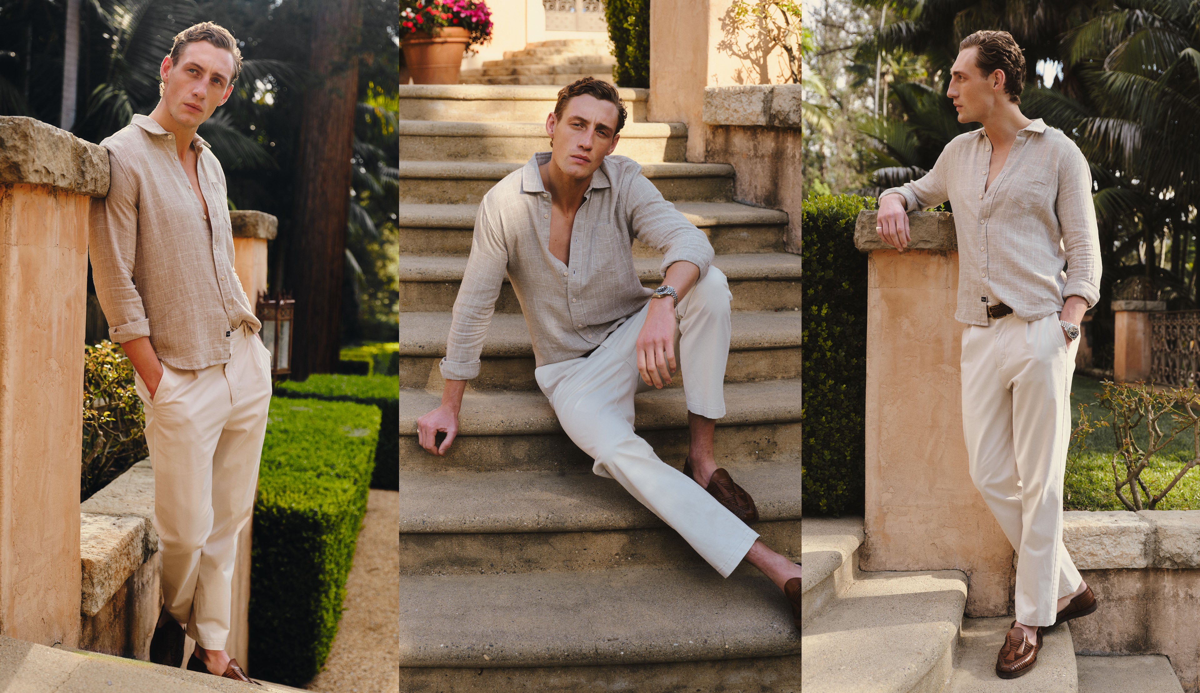 Man in beige shirt and white pants posing outdoors on stone steps.