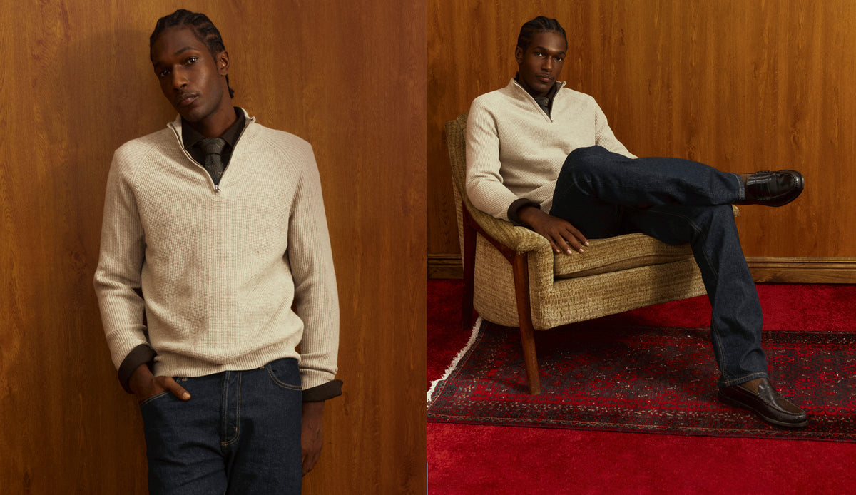 Two shots of a man in a cream waffle-knit quarter-zip sweater over a dark collared shirt and tie, with dark denim; one leaning against a wood-paneled wall, one seated in a vintage armchair on a red rug in leather loafers.