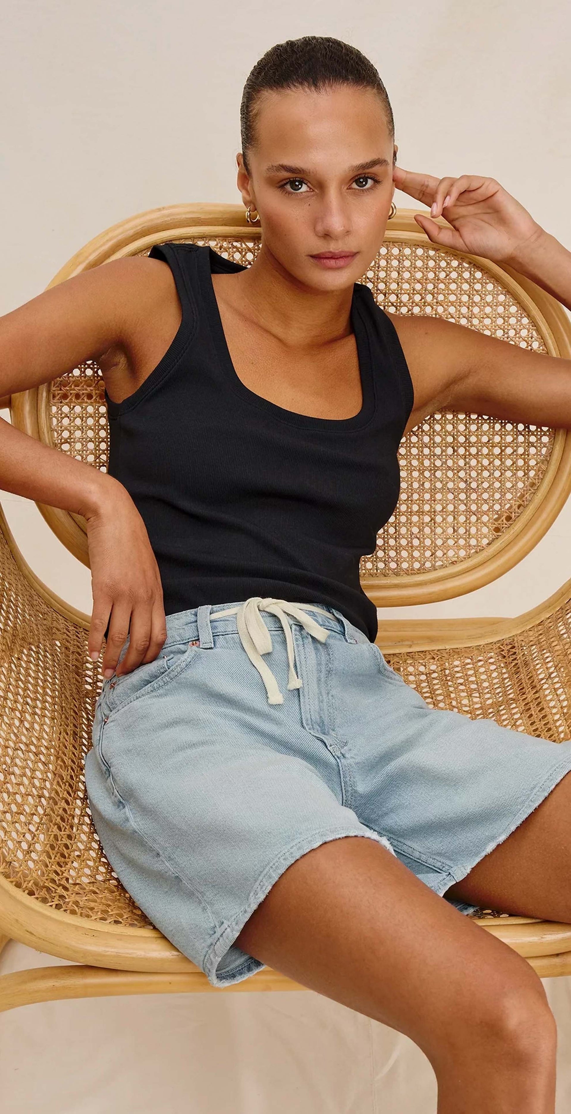 Woman wearing a black tank top and light blue denim shorts