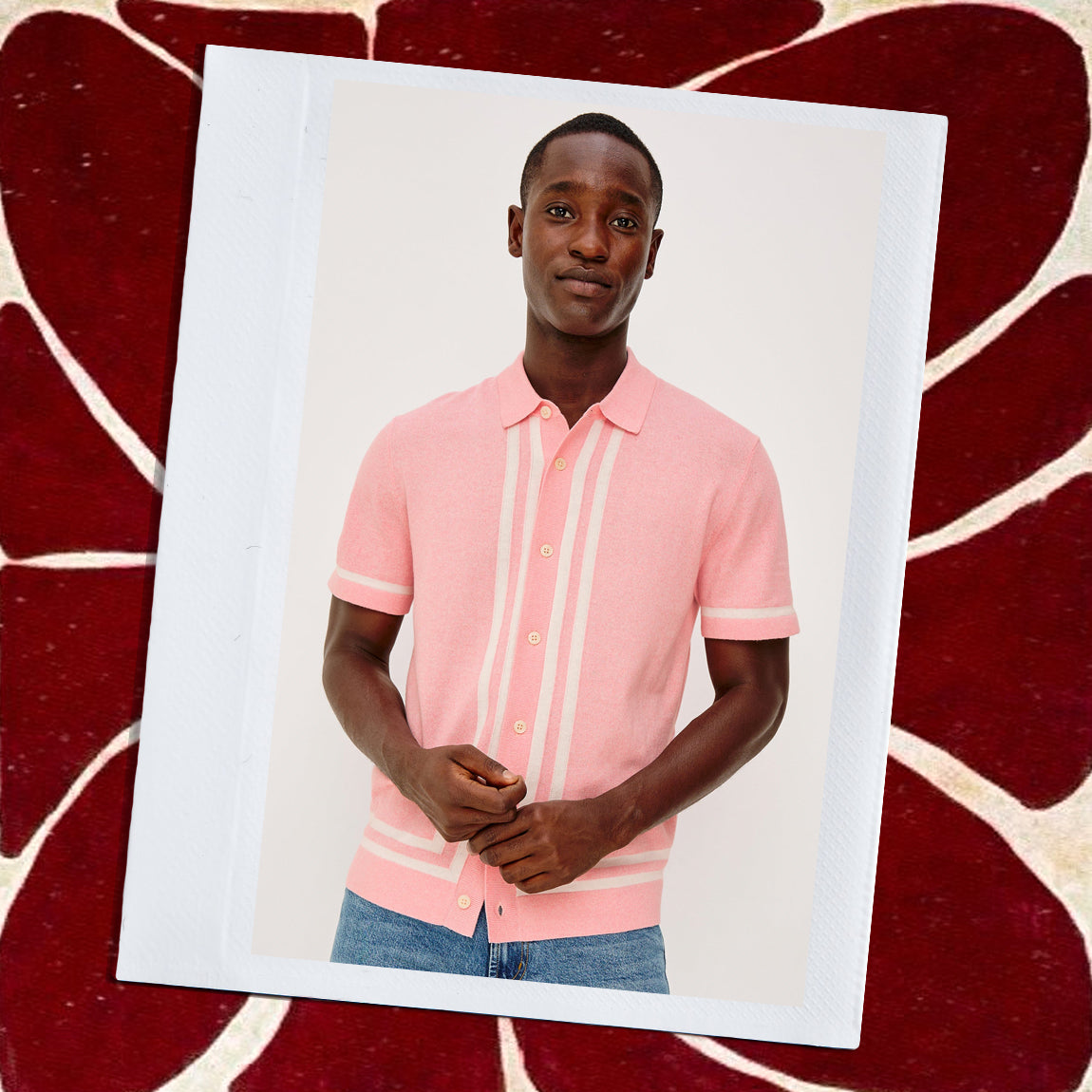 Man wearing a pink polo shirt with white stripes on a decorative red background.
