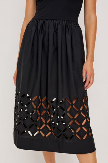 Nadya is a midi dress with a soft scoop neck bodice and a lightweight skirt in Black Colorway. The skirt features engineered cutouts from mid-thigh to hem and includes discreet on-seam pockets. Close up of cutout details on model.