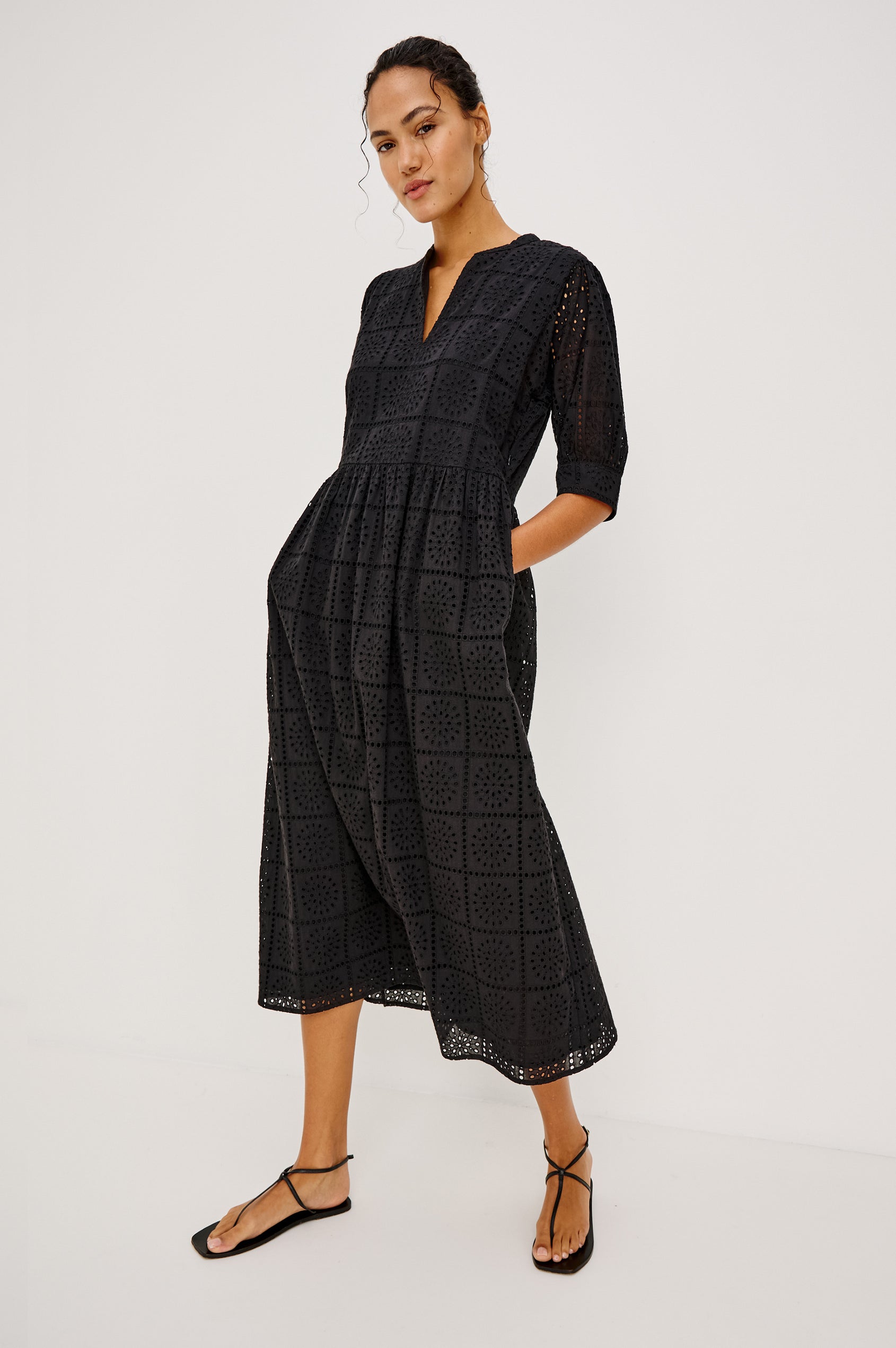 Nella Smock Maxi Dress in Cotton With Grid Eyelet Embroidery Lined Body Split Band V-Neckline Drop Waist Gathered Skirt and Short Puff Sleeves With Fitted Cuffs in Black Colorway - Full Body Front View Featured on Model