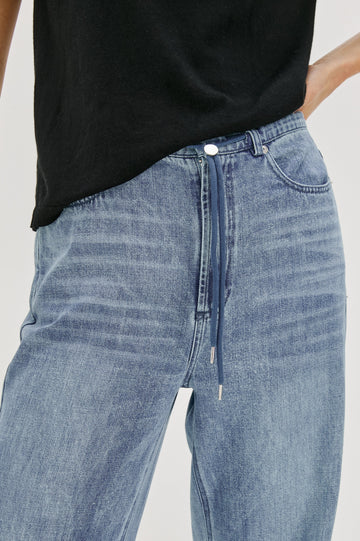 Normandie Lightweight 5-Pocket Denim Wide Leg Pant with front zipper button fly and a drawstring tie at waist in Antique Blue Colorway. Front View Close up of Details Featured on Model.