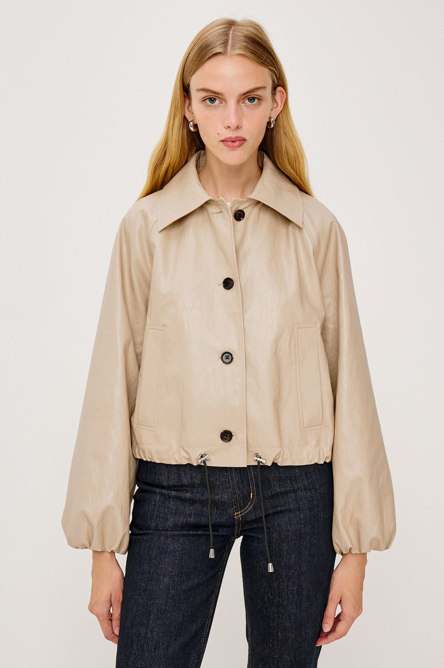 North Cropped Jacket in Faux Leather With Loose Boxy Fit, Oversized Collar, Front Buttons, Side Pockets, Drawstring Hem, Long Lantern Sleeves With Elastic Cuffs in Dune Colorway - Upper Body Front View Featured on Model