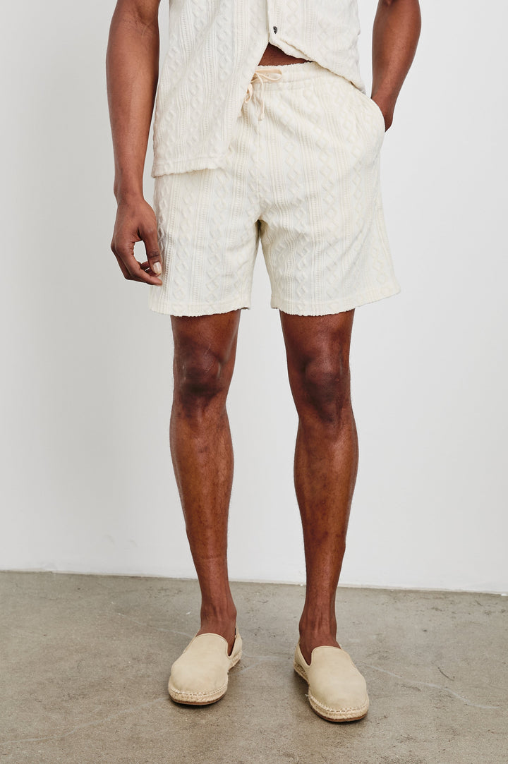 Nova Shorts with a Drawstring Waist, a Raised Jacquard Pattern, Two Front Pockets and a Back Patch Pocket in Ecru Colorway - Front View Featured on Model